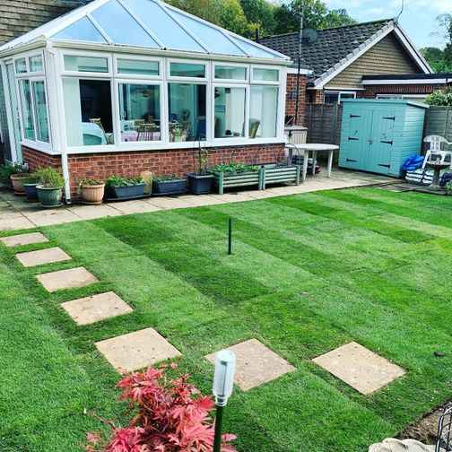 Landscaped garden with grass and patio tile pathway